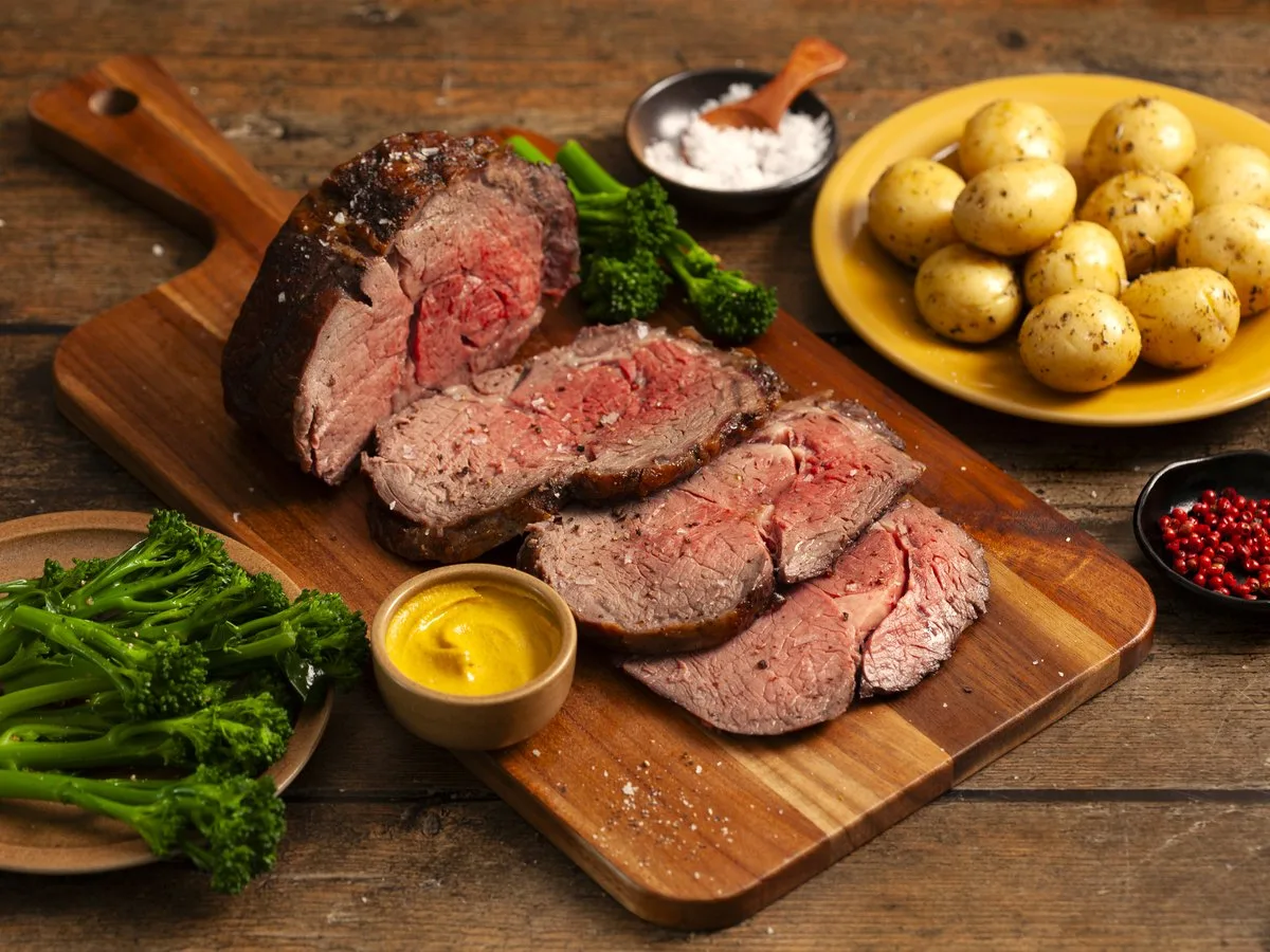 Sliced cooked beef, pink inside, with mustard beside it.